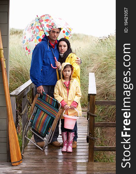 Family on beach with umbrella looking sad