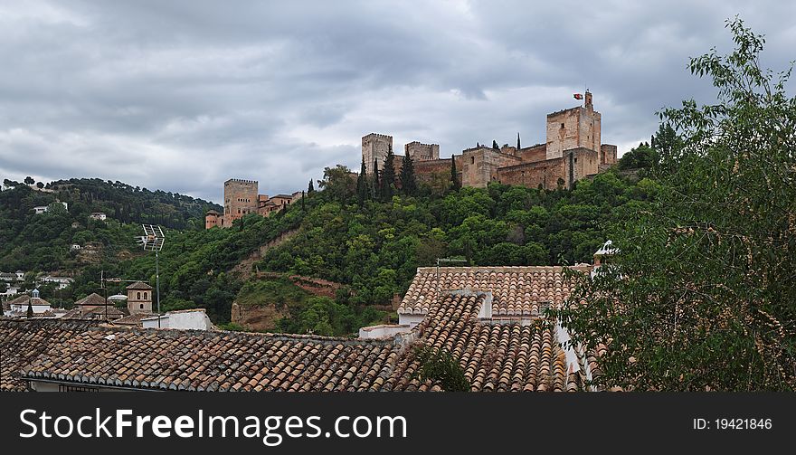 Alhambra palace above the Granada roofs in cloudy day, Spain. Alhambra palace above the Granada roofs in cloudy day, Spain