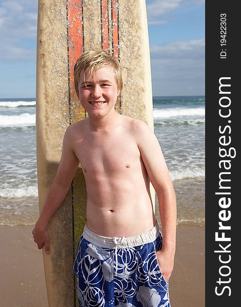 Teenage boy with surfboard smiling at camera