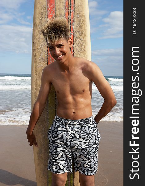 Teenage boy with surfboard smiling at camera