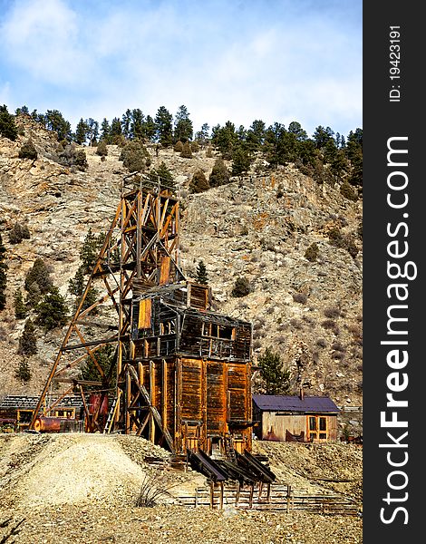 The antique remains of a century old gold mine clings to the side of a wilderness hill. The antique remains of a century old gold mine clings to the side of a wilderness hill.