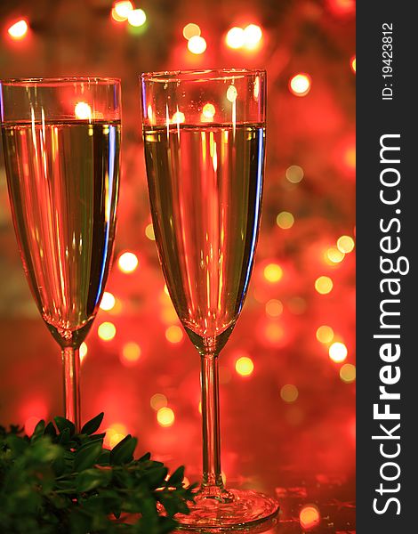 Close-up of champagne in glasses, green twig and blured lights on background. Close-up of champagne in glasses, green twig and blured lights on background