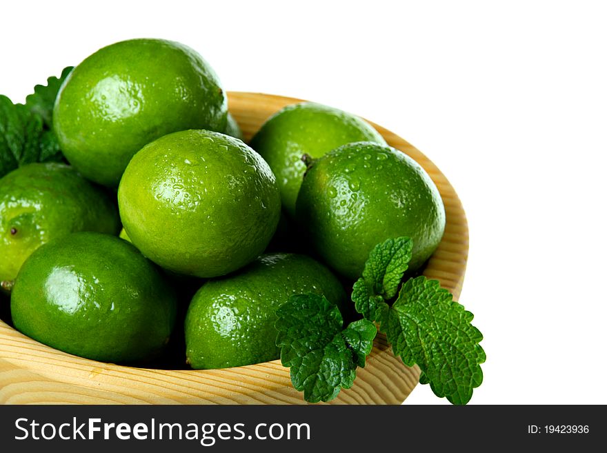 Fresh limes in wooden bowl, isolated on white