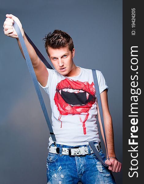 Portrait of impudent beautiful young man with braces on grey background.