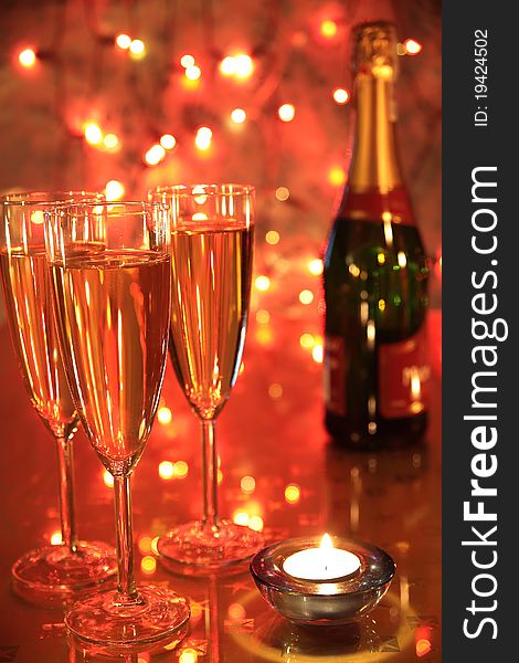 Champagne in glasses, cadlelight and blured lights on red background. Champagne in glasses, cadlelight and blured lights on red background.