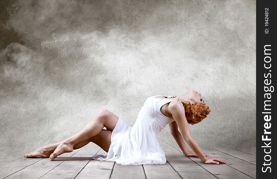 Woman dancer seating posing on background