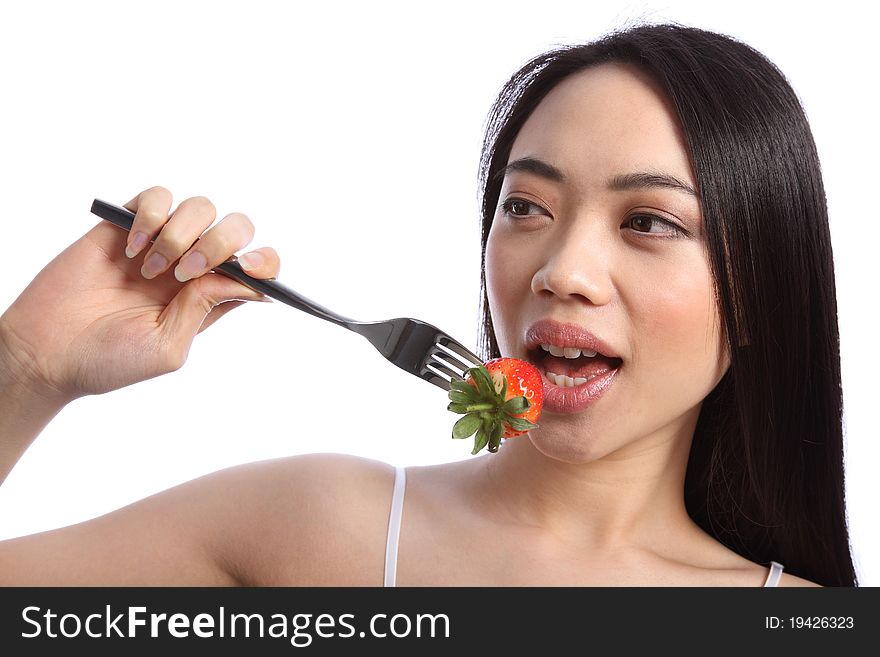 Exotic and beautiful young oriental girl, with long black hair, about to bite into a fresh strawberry fruit on a fork. Exotic and beautiful young oriental girl, with long black hair, about to bite into a fresh strawberry fruit on a fork.