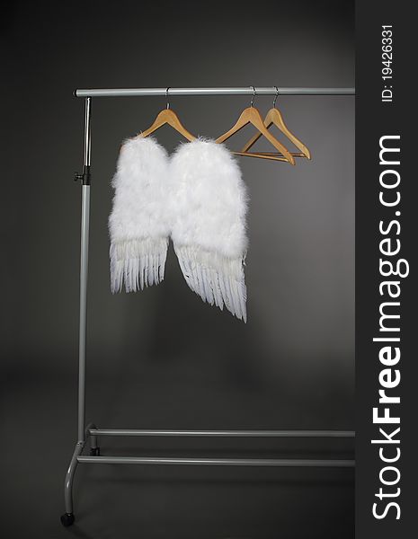 Wooden hangers and white wings on the grey background