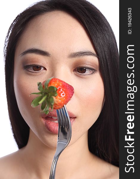 Going cross eyed, an exotic and beautiful young oriental girl, with long black hair ready to eat a fresh strawberry fruit on a fork. Going cross eyed, an exotic and beautiful young oriental girl, with long black hair ready to eat a fresh strawberry fruit on a fork.