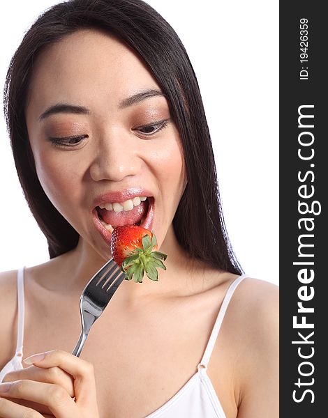 Chinese beautiful teenager girl with long black hair, mouth wide open, eating a fresh strawberry fruit on a fork. Chinese beautiful teenager girl with long black hair, mouth wide open, eating a fresh strawberry fruit on a fork.