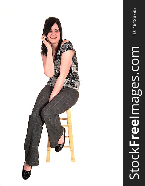 A young business woman sitting on a chair and talking on her cell phone, in slakes and high heels, for white background. A young business woman sitting on a chair and talking on her cell phone, in slakes and high heels, for white background.