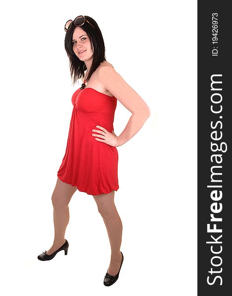 A beautiful young woman in a red dress and black hair standing in profile in the studio, for white background. A beautiful young woman in a red dress and black hair standing in profile in the studio, for white background.