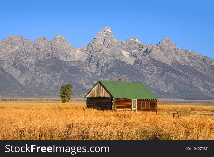 Abandoned house in prairie landscape with Grand Tetons background
