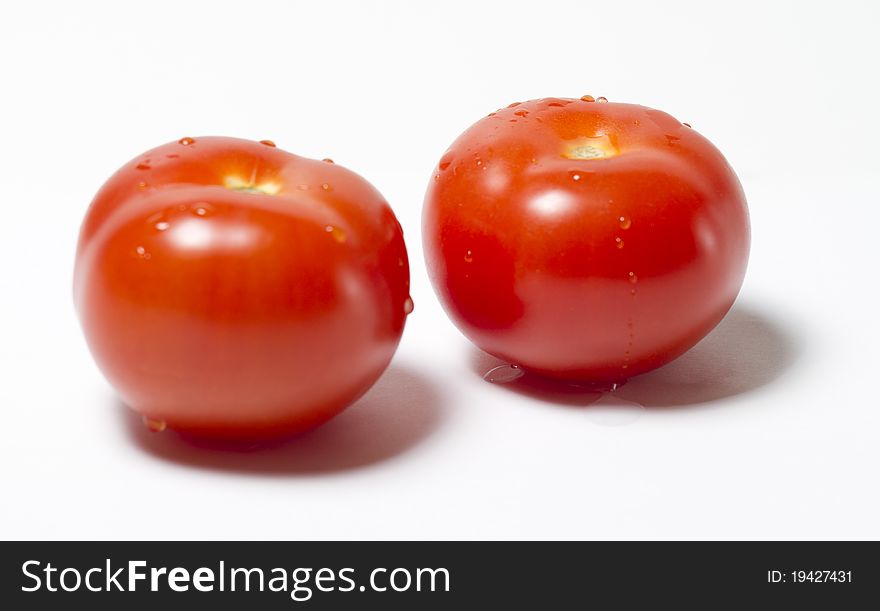 Two red tomatos wet on white background
