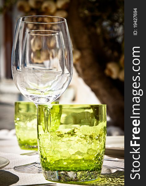 Table setting for al fresco dining in a picturesque village street with olive tree and garlic in the background, portrait. Table setting for al fresco dining in a picturesque village street with olive tree and garlic in the background, portrait.