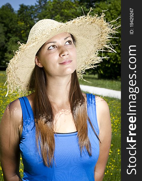 Beautiful young girl in the park with straw hat