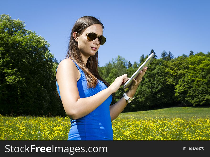 Beautiful young girl in the park with tablet computer