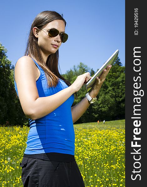 Beautiful young girl in the park with tablet computer