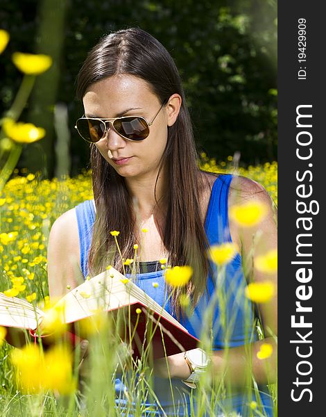 Beautiful young girl in the park reading a book