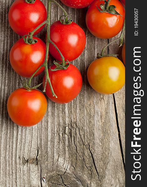 Top view on branch of fresh cherry tomatoes on old wooden background