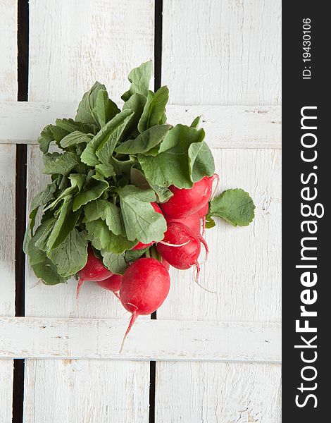 Top view on bunch of fresh radishes on white wooden table