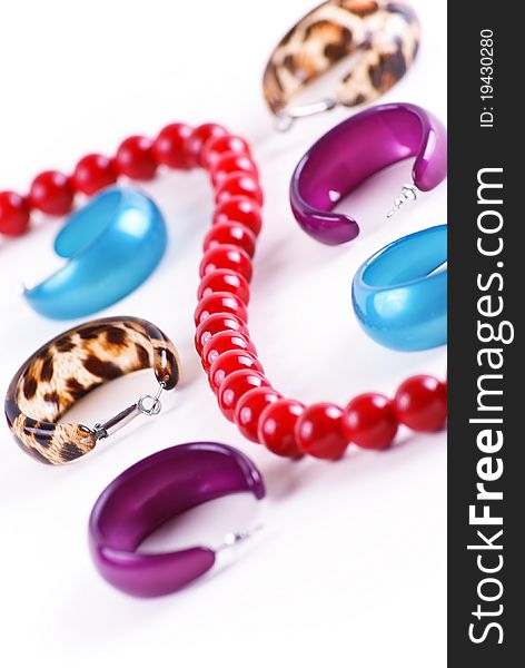 Different ear-rings and red beads on white background in studio