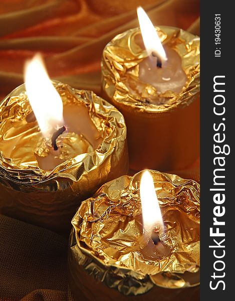 Three small burning golden candles, vertical composition