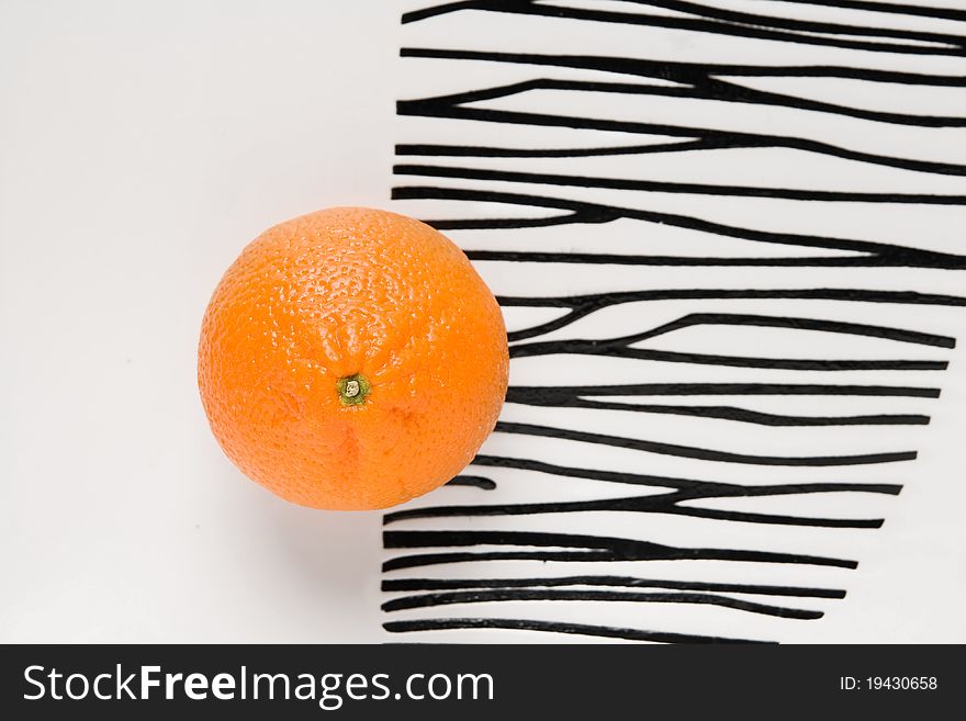 Orange on a striped plate. Orange on a striped plate