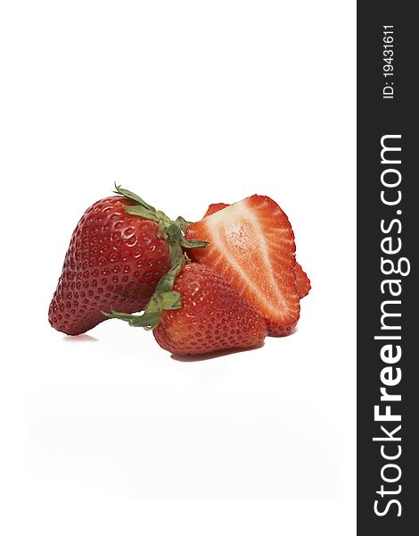 A group of sliced and unsliced strawberries isolated on a white background.