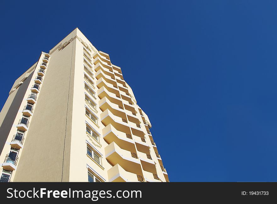 Dwelling-house building in a center a city on a background blue sky in foreshortening