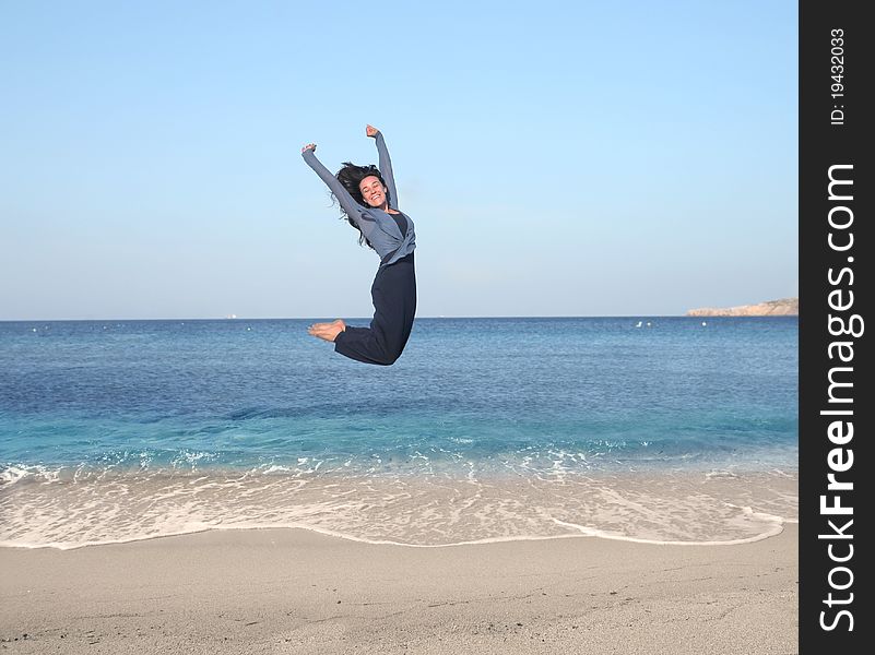Smiling woman jumping on a beach. Smiling woman jumping on a beach