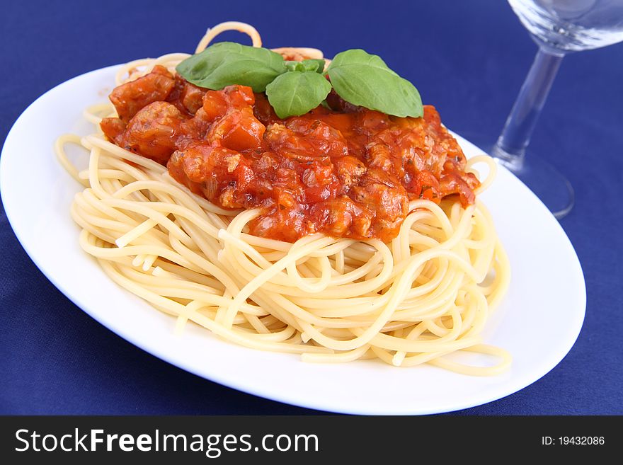Spaghetti bolognese on a plate and a wineglass