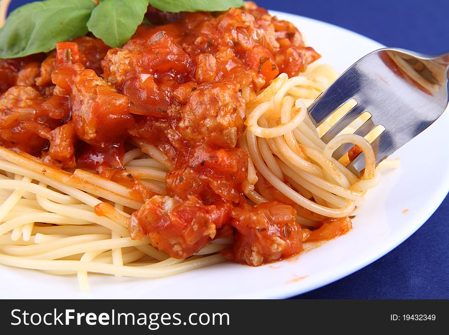 Spaghetti bolognese on a plate being eaten with a fork