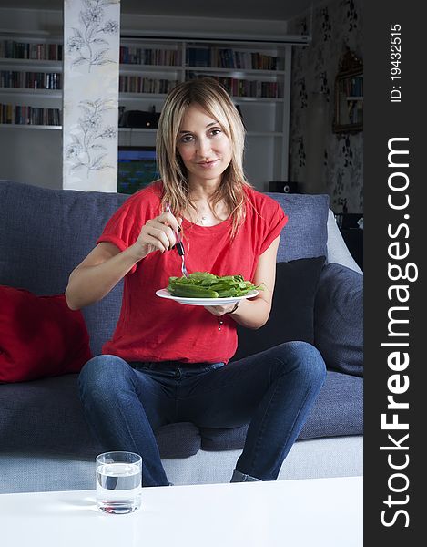 Beautiful blond woman eating green leaves as a healthy meal