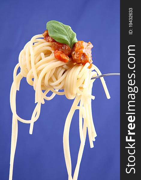 Spaghetti bolognese with basil leaves on a fork