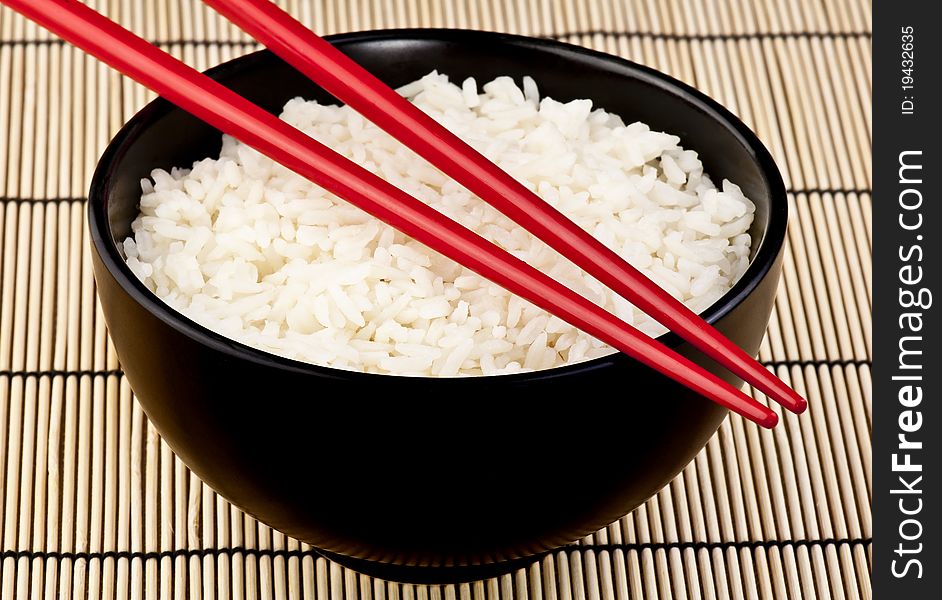 A bowl of rice with chop sticks representing an Asian staple. A bowl of rice with chop sticks representing an Asian staple