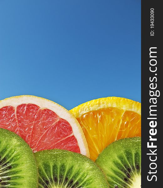 Kiwi, orange, grapefruit on a background blue sky