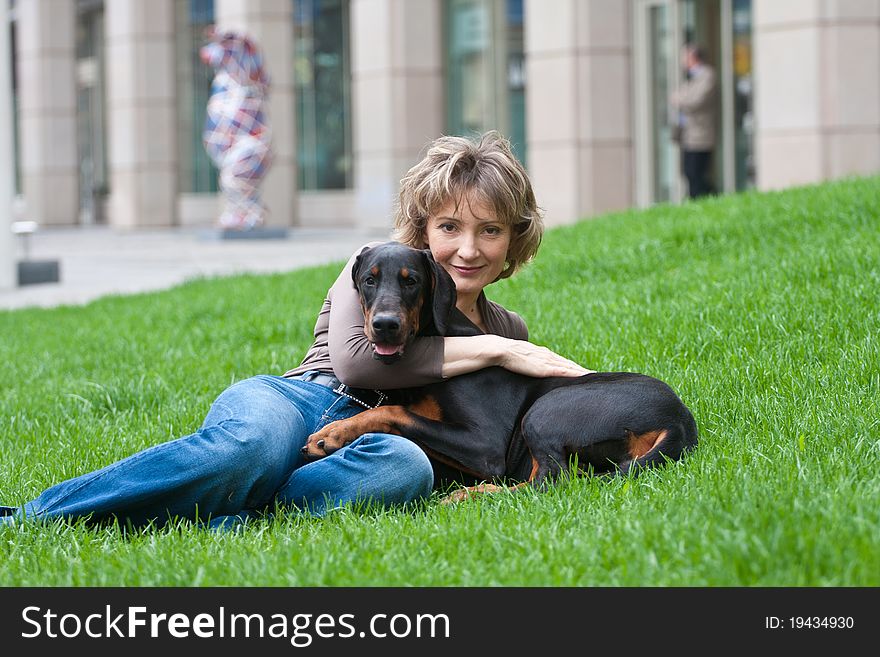 The young woman with a doberman dog on a grass. The young woman with a doberman dog on a grass