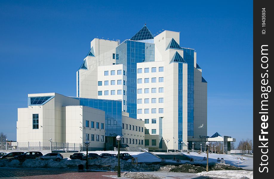 A large modern office building against the blue sky and snow