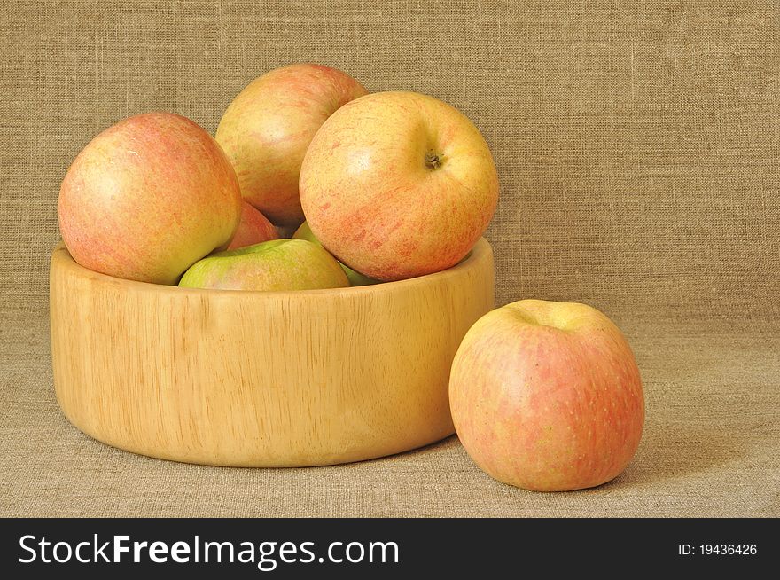 Apples in a wooden plate against from a sacking