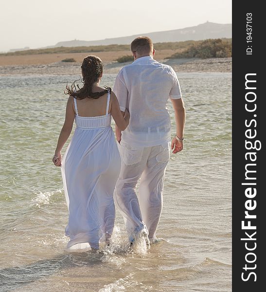 Young newlyweds walking on a tropical beach