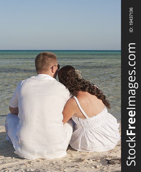 Young newly married couple sitting on a tropical beach. Young newly married couple sitting on a tropical beach