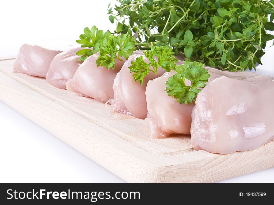 Raw chicken breasts on chopping board with herbs