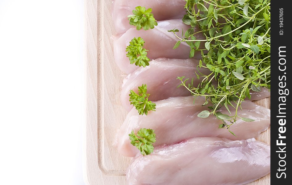 Raw chicken breasts on chopping board with herbs