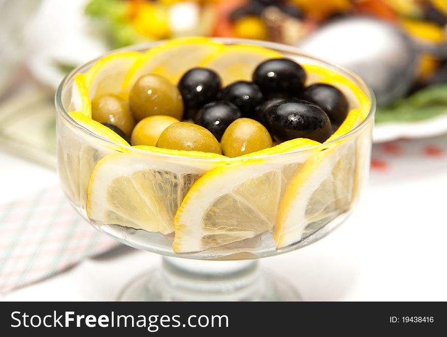 Green and black olives in olive oil with lemon slice in salad bowl. Green and black olives in olive oil with lemon slice in salad bowl