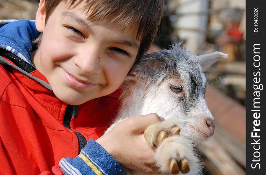Teenage boy portrait with young white goatling smiling outdoor. Teenage boy portrait with young white goatling smiling outdoor