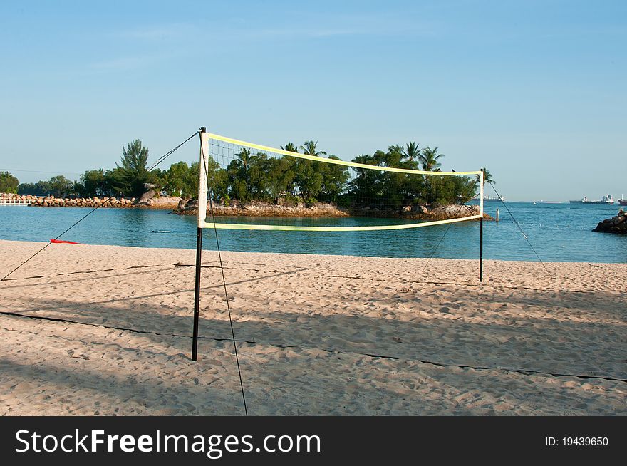 Beach volley ball net with palm tree island at the background