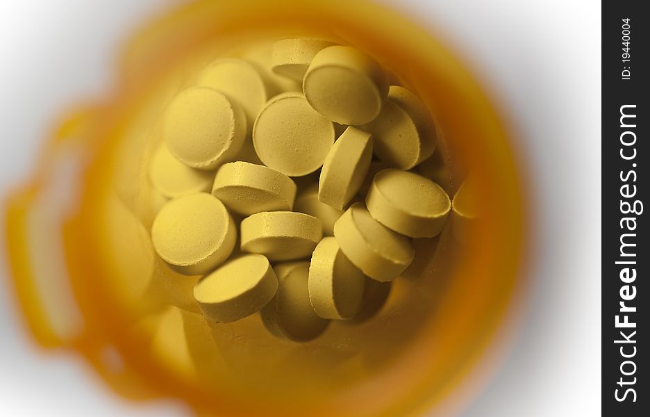 Macro view of pills shot in a yellow medicine bottle