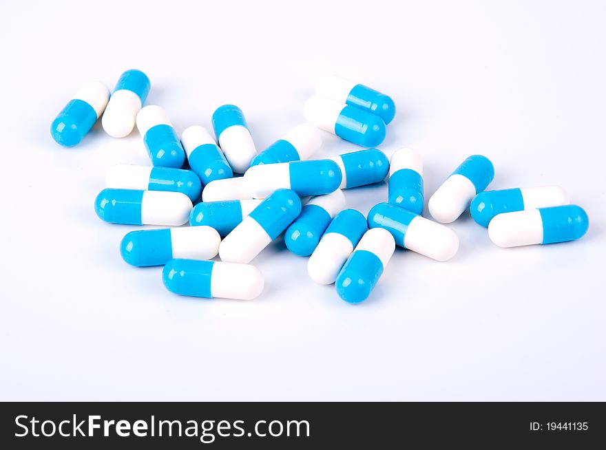 blue and white capsules of medicament on white background