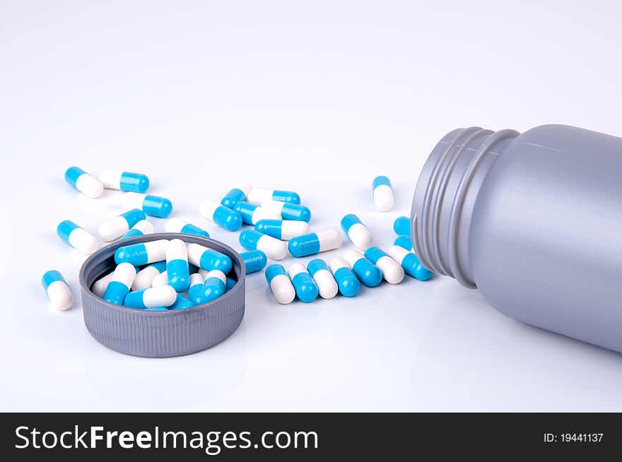 Plastic container with medicine in blue and white capsules. Plastic container with medicine in blue and white capsules